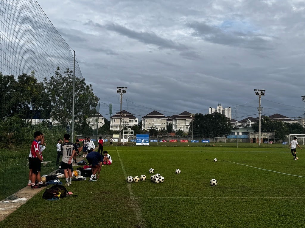 サッカーグラウンドで、ユニフォーム姿の選手たちがボールを使って練習している様子。