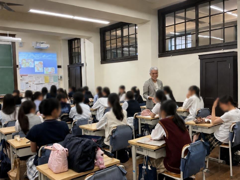 教室で、男性講師が多くの生徒に向かって話している授業中の様子。