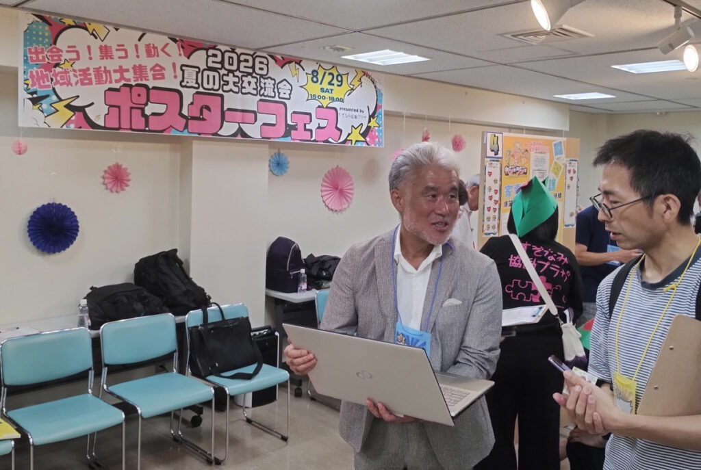 ポスターフェスの会場で、参加者に活動を説明する戸田隆夫代表